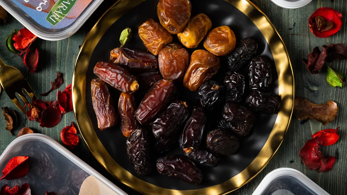 Kurma dalam mangkuk kuningan bersama beberapa wadah simpan tertutup, dilihat dari atas
